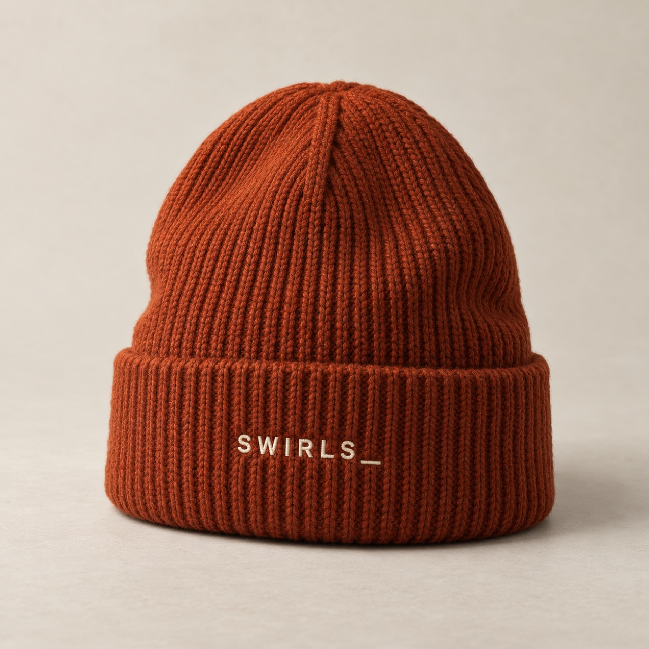 Rust rib-knit Swirls beanie concept with a folded cuff and small cream embroidered wordmark